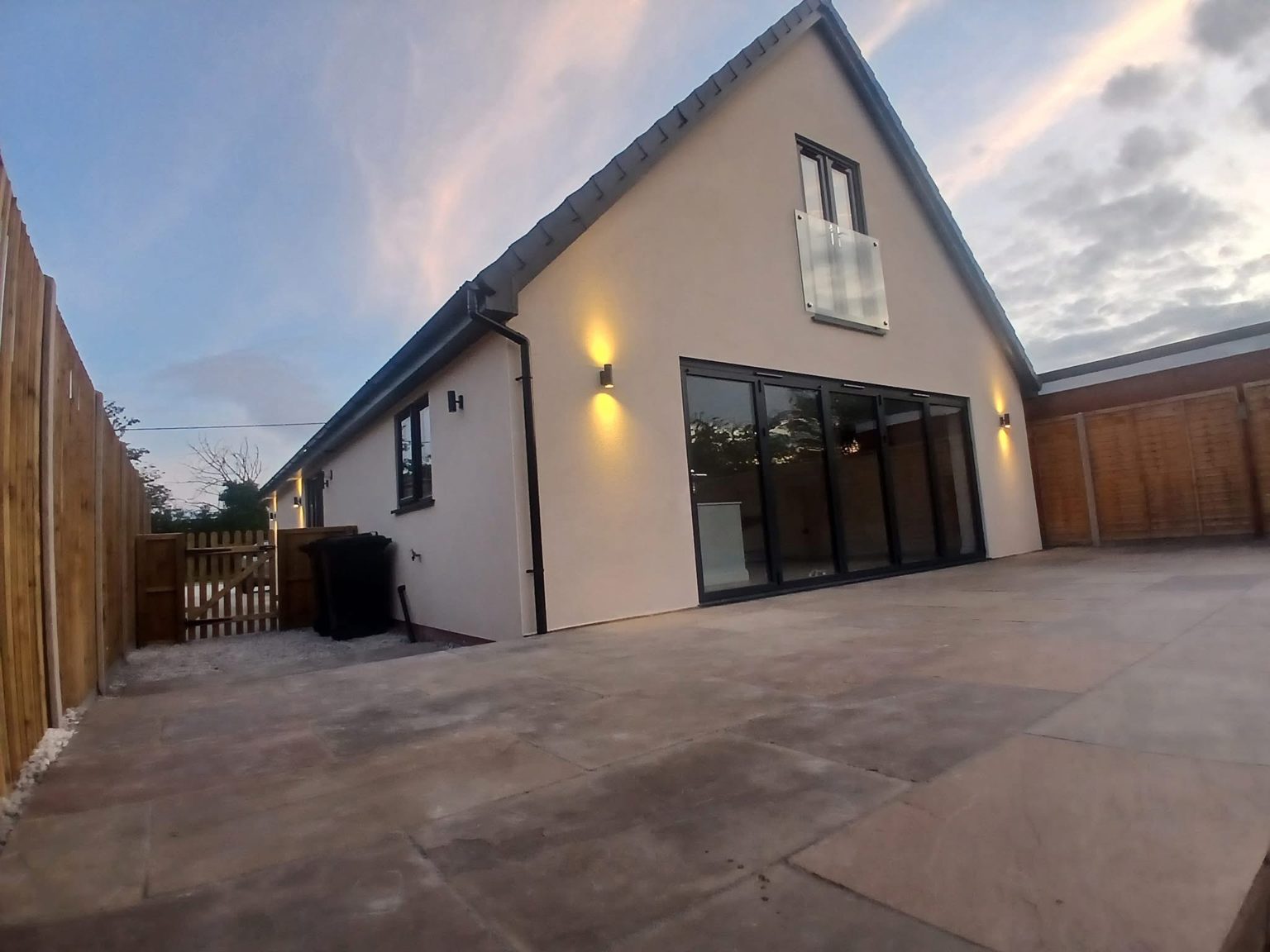 Newly finished bungalow at dusk with outdoor wall lights on