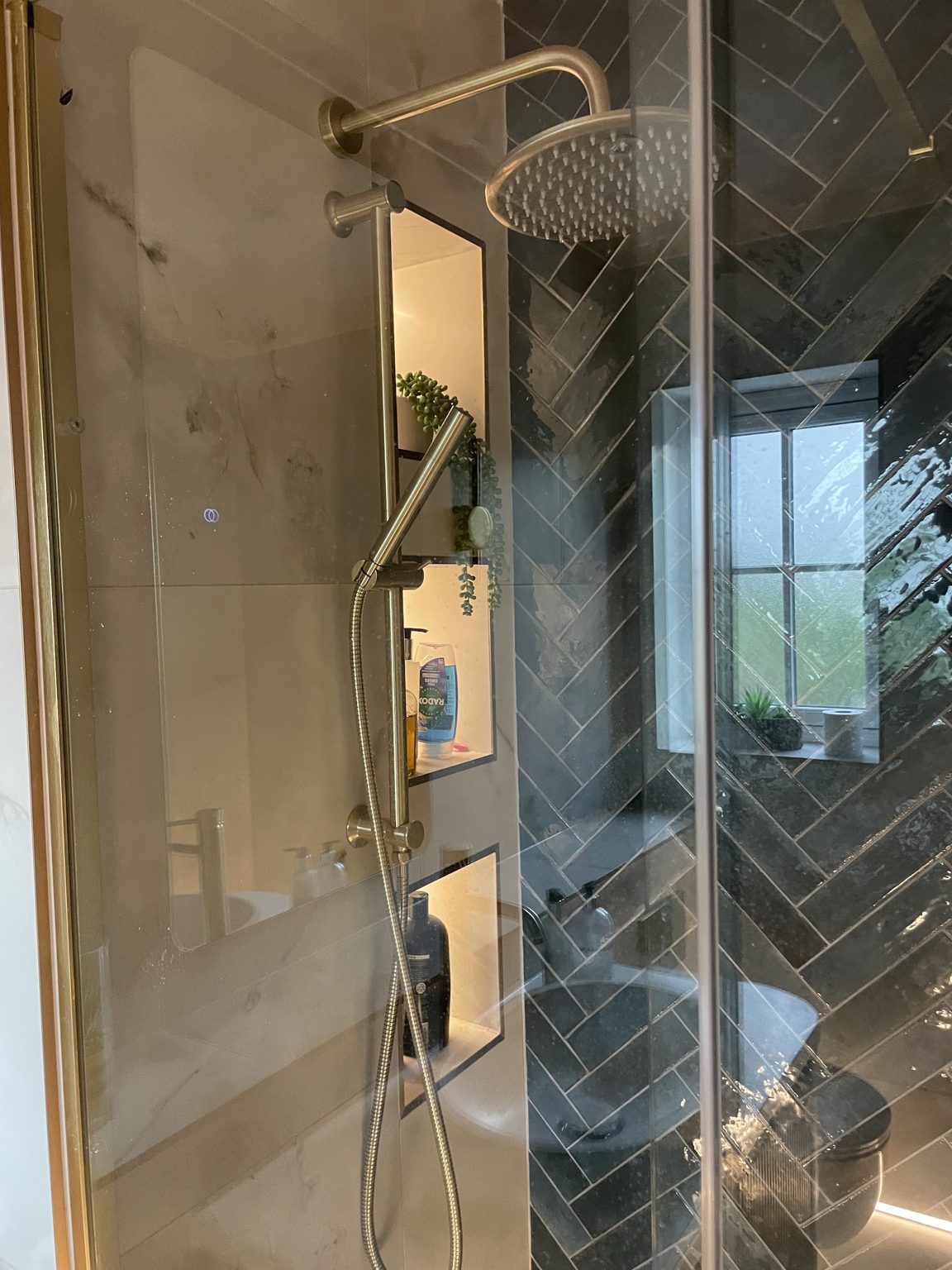 Walk-in shower with lit wall niches and brass fittings