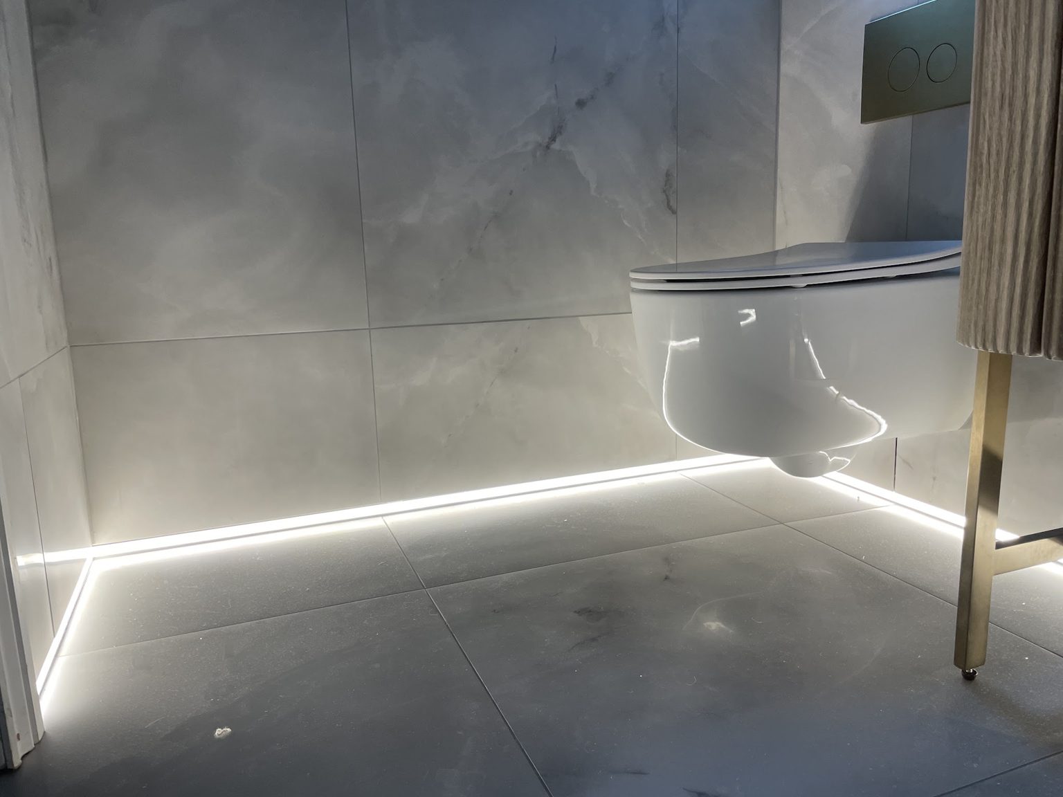 Low-level LED strip lighting beneath a wall-hung toilet
